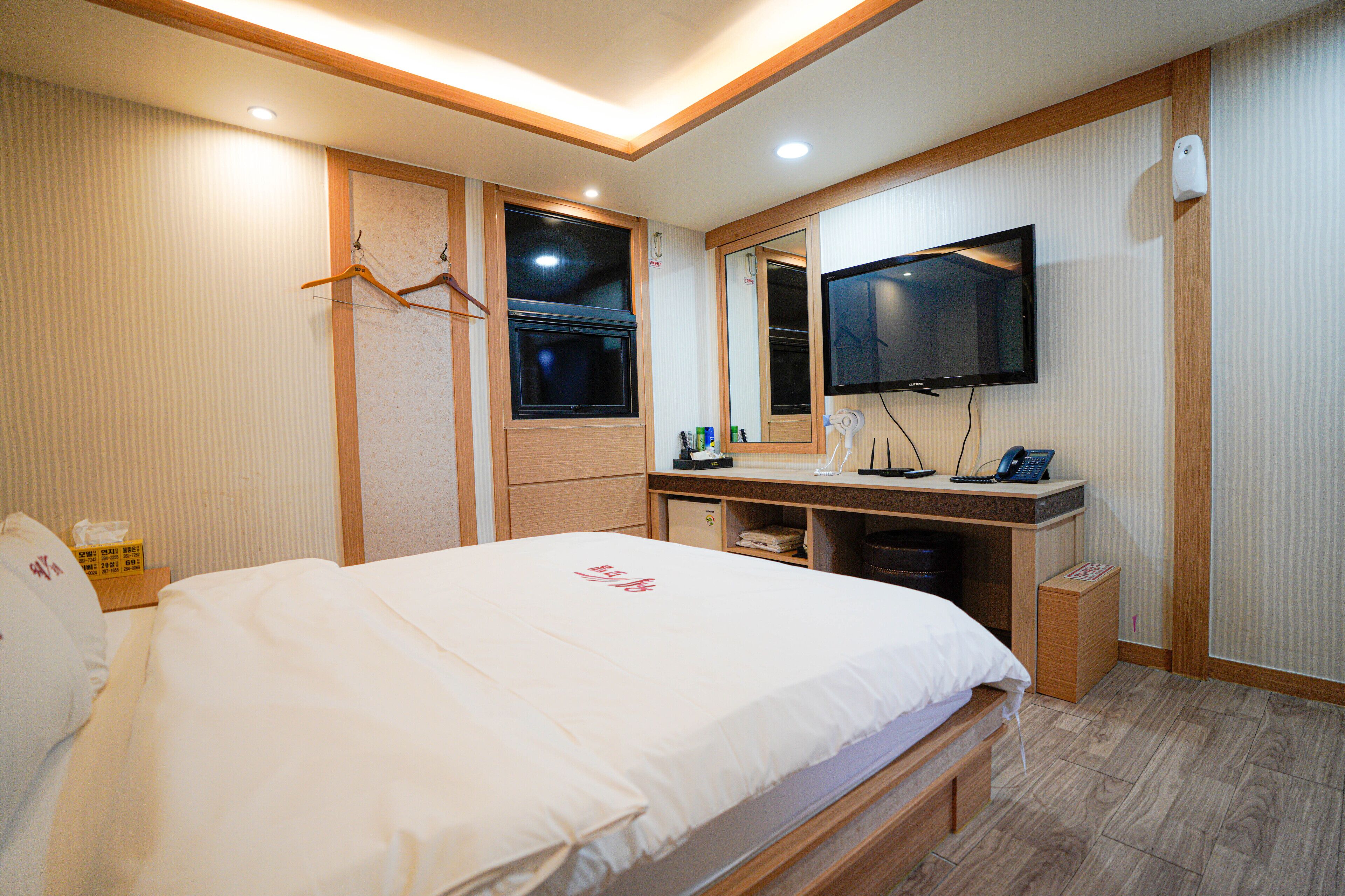 Habitación de hotel con cama, televisión, escritorio y espejo.
