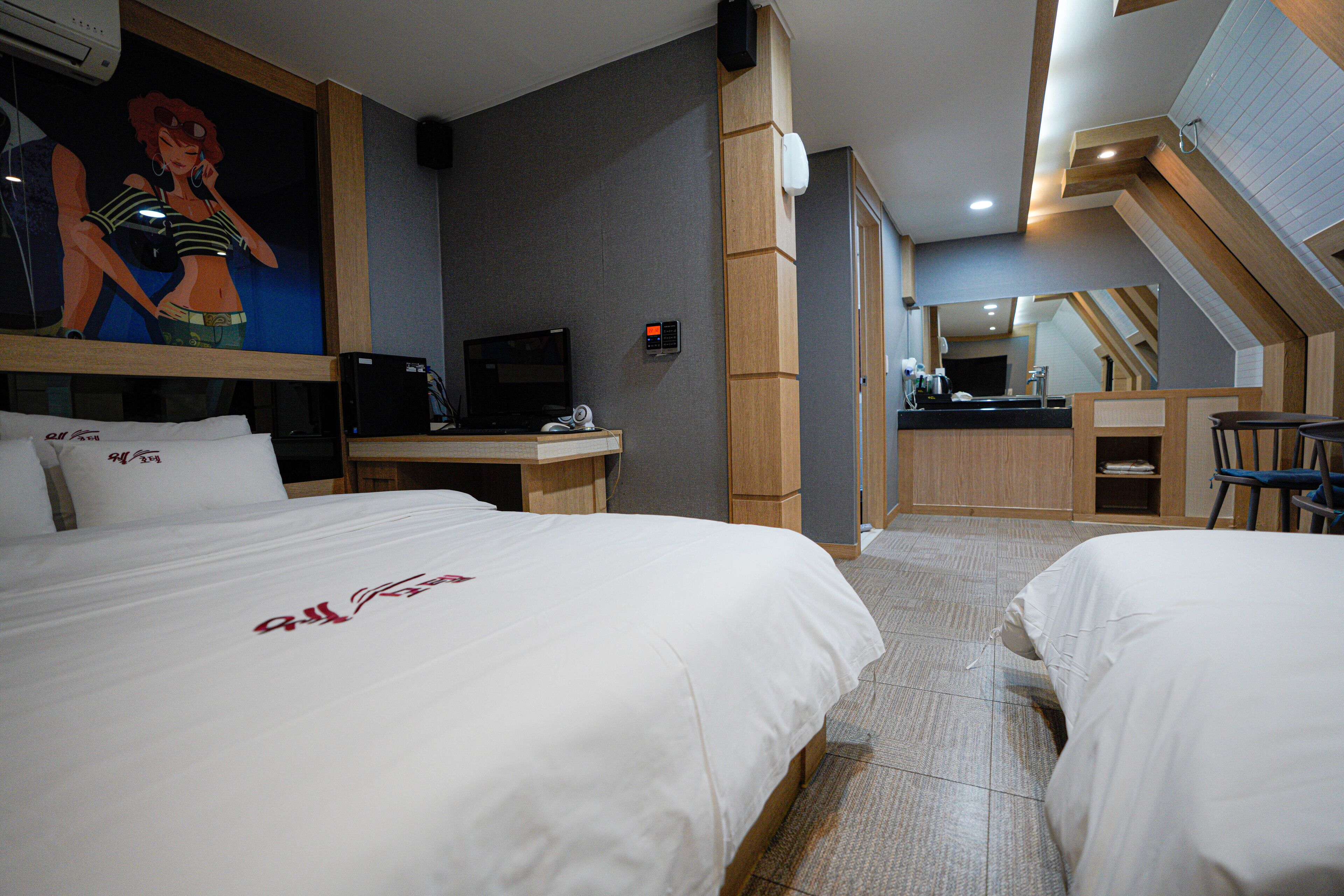 Habitación de hotel con dos camas, un escritorio, una computadora y una kitchenette.