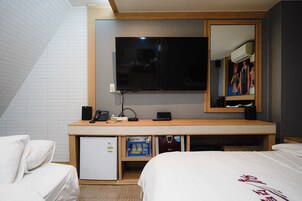 Una habitación de hotel con cama, escritorio con televisor, refrigerador y minibar.