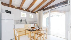 Eine moderne Küche mit Holzbalken, weißen Schränken und einem Essbereich mit Tisch und Stühlen.