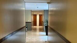 A hallway with wooden flooring and mirrored walls, leading to a door at the end. - Acogedor Apartasuite Cerca al Parque de la 93 (Bogotá)