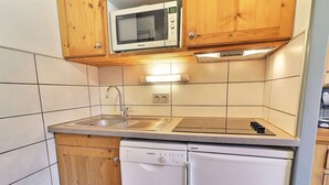 Eine kleine Küche mit Holzausstattung, integriertem Mikrowellenherd, Spüle und Geschirrspüler.