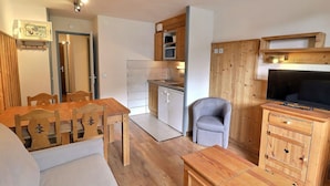 A compact living space with a dining area, kitchenette, and a television.