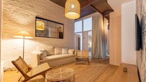 A modern living room with a sofa, a wicker chair, a round wicker ottoman, a floor lamp, and a large window with curtains. - Triana Acacias by Valcambre  (Seville)