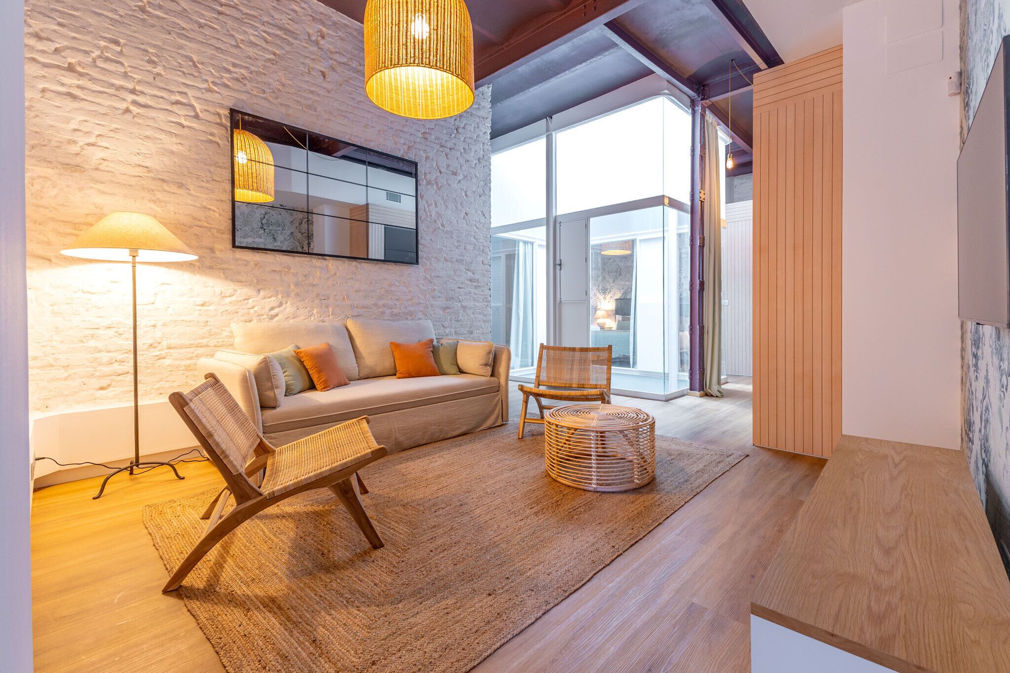 Ein modernes Wohnzimmer mit Sofa, Sessel, Stehlampe und einem gewebten Korb.