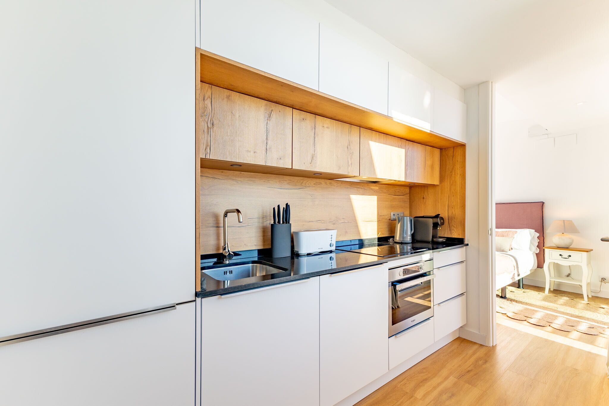 Une cuisine moderne avec des armoires blanches, un plan de travail en bois et des appareils électroménagers en acier inoxydable.