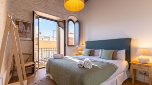 A bedroom with a large bed, a wooden ladder, a balcony with a view, and a hanging light fixture. - Triana Acacias by Valcambre  (Seville)