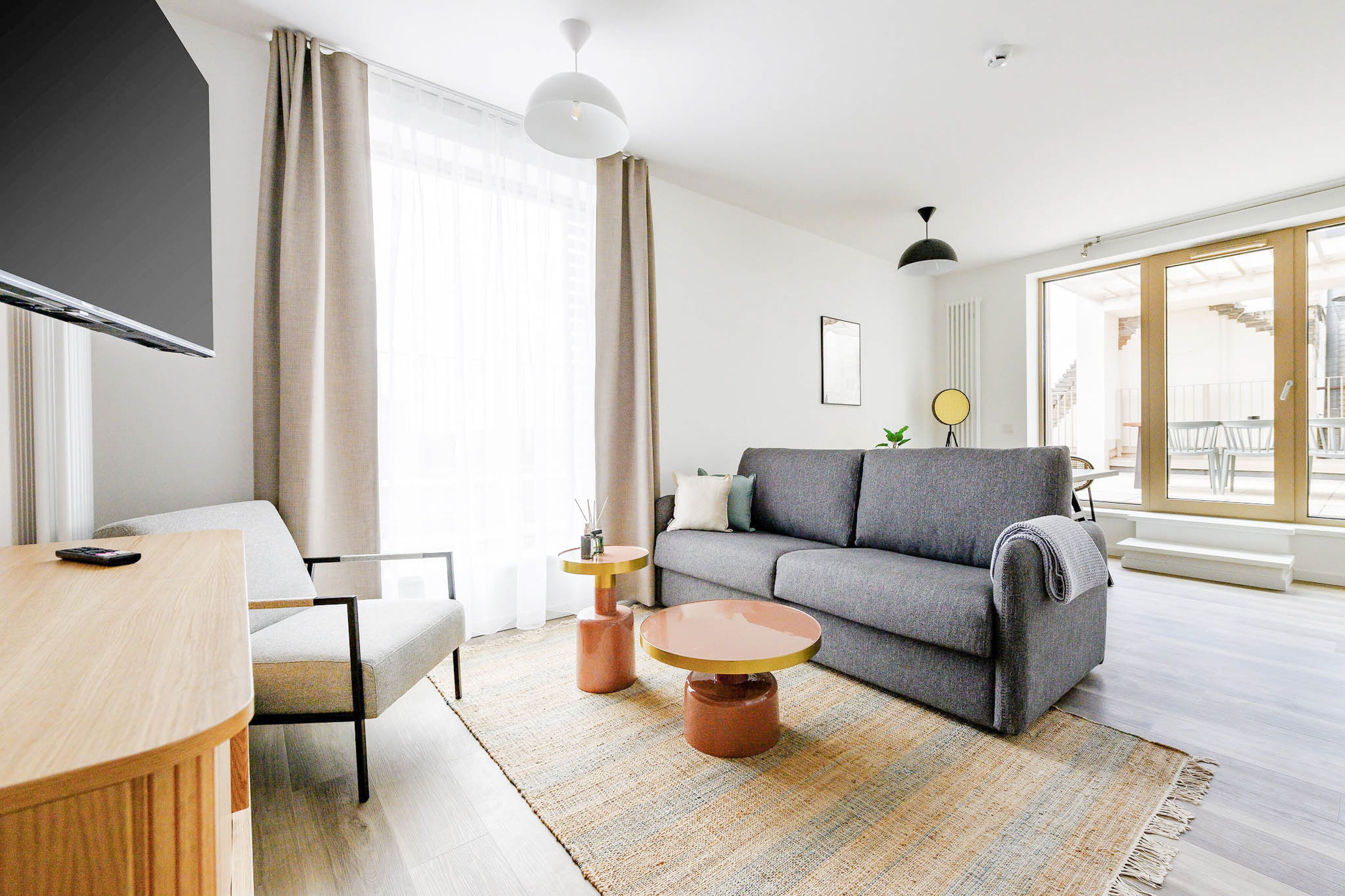 A modern living room with a grey sofa, a round coffee table, and a TV on a wooden stand.