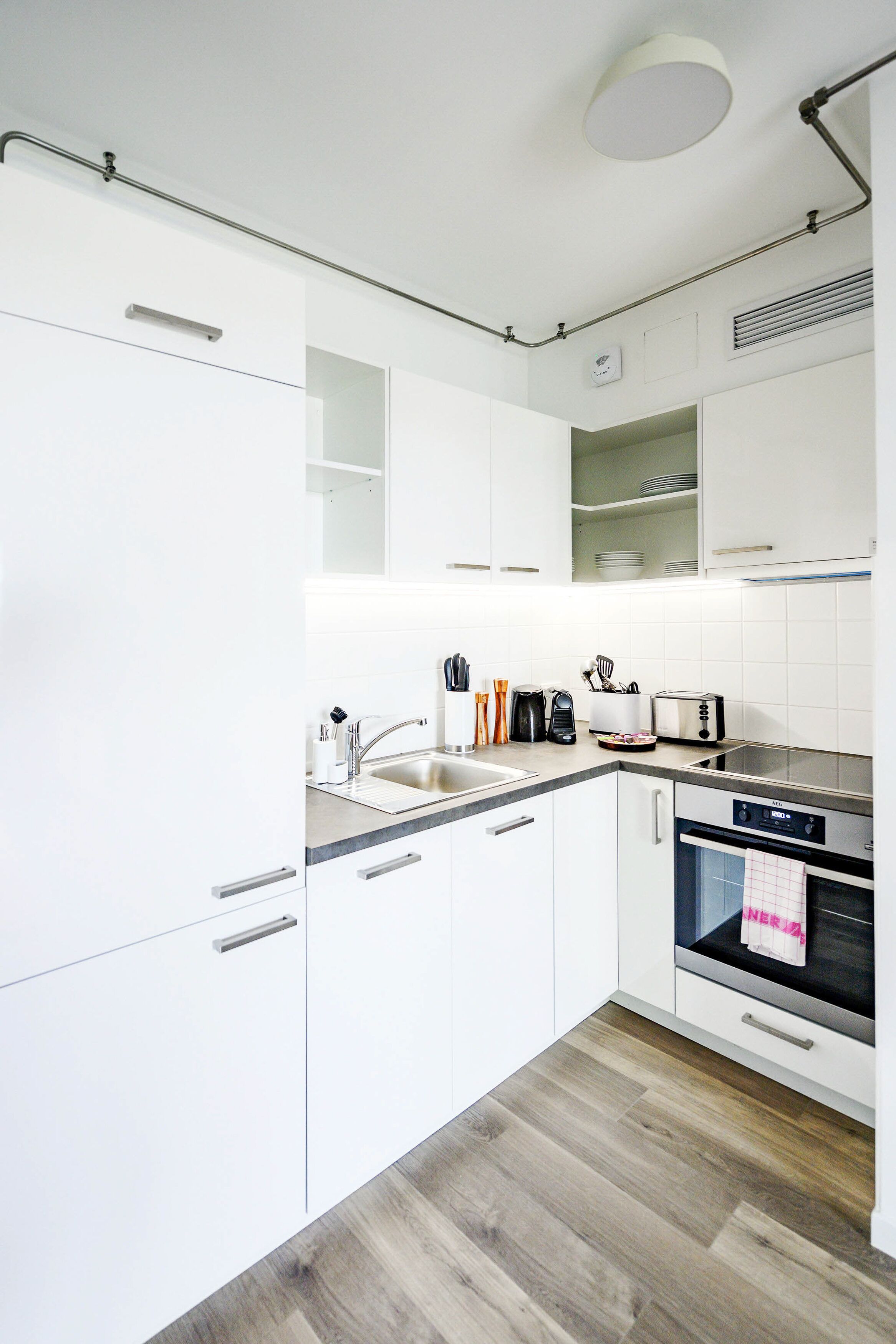 A modern kitchen with white cabinetry, a stainless steel sink, a toaster, and a built-in oven.