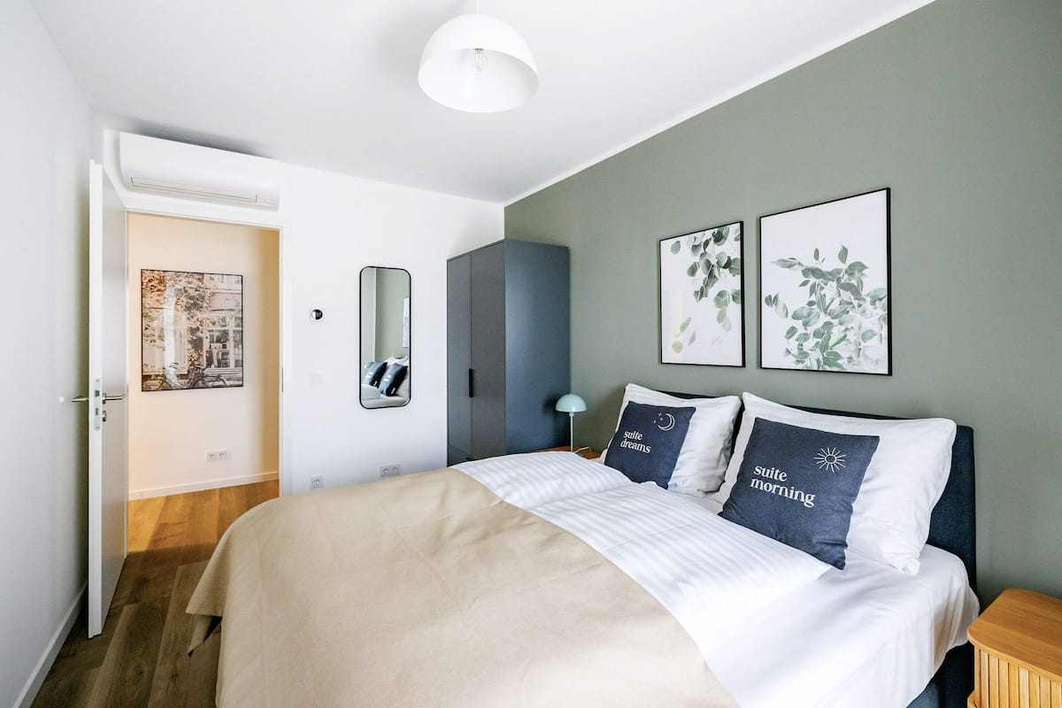 Um quarto moderno com cama, guarda-roupa, espelho e obras de arte na parede.