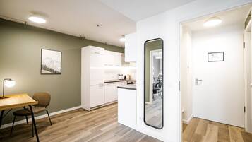 A modern kitchen with white cabinets, a dining area with a table and chairs, and a large mirror.