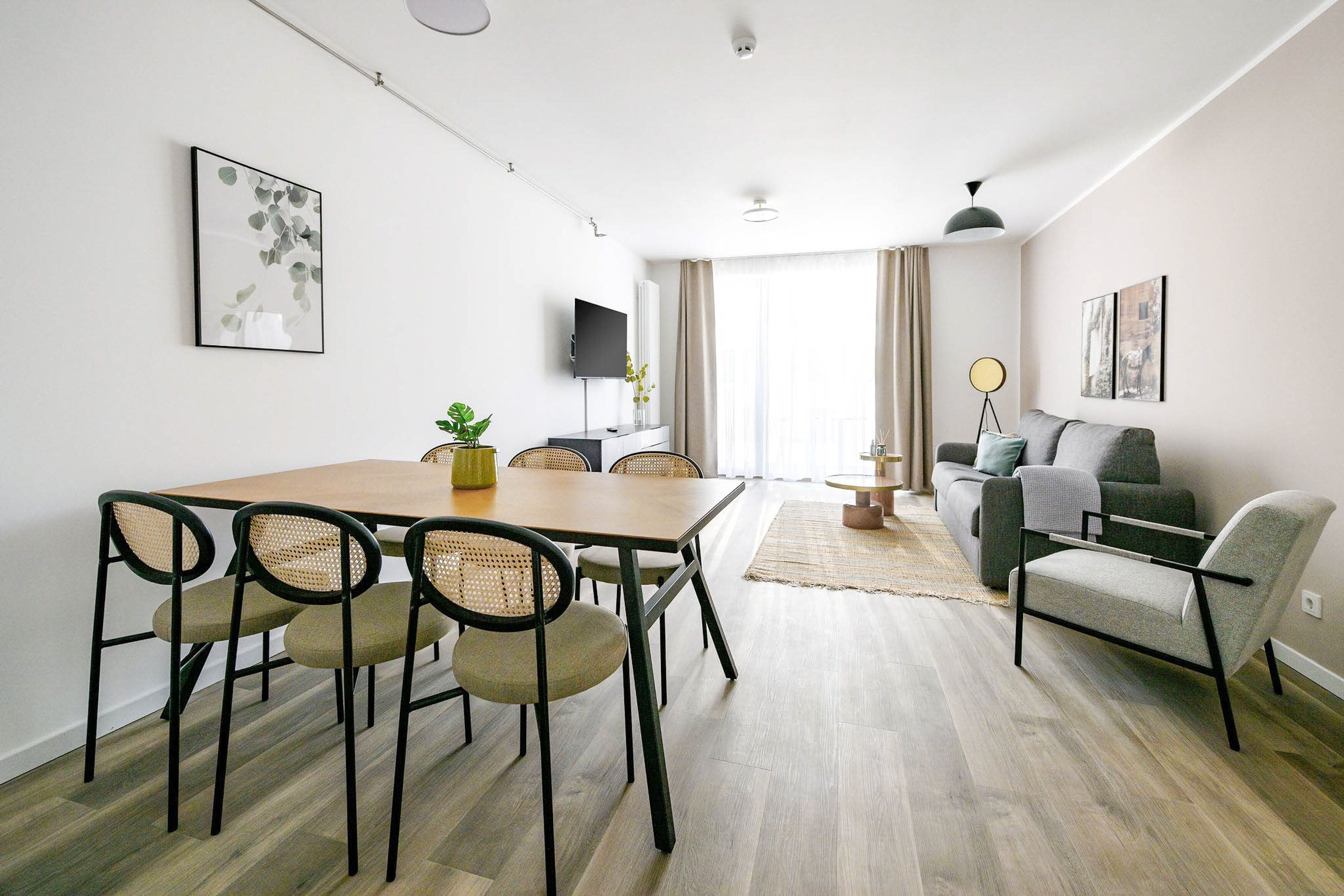 A modern living room with a dining area, a sofa, and a TV.