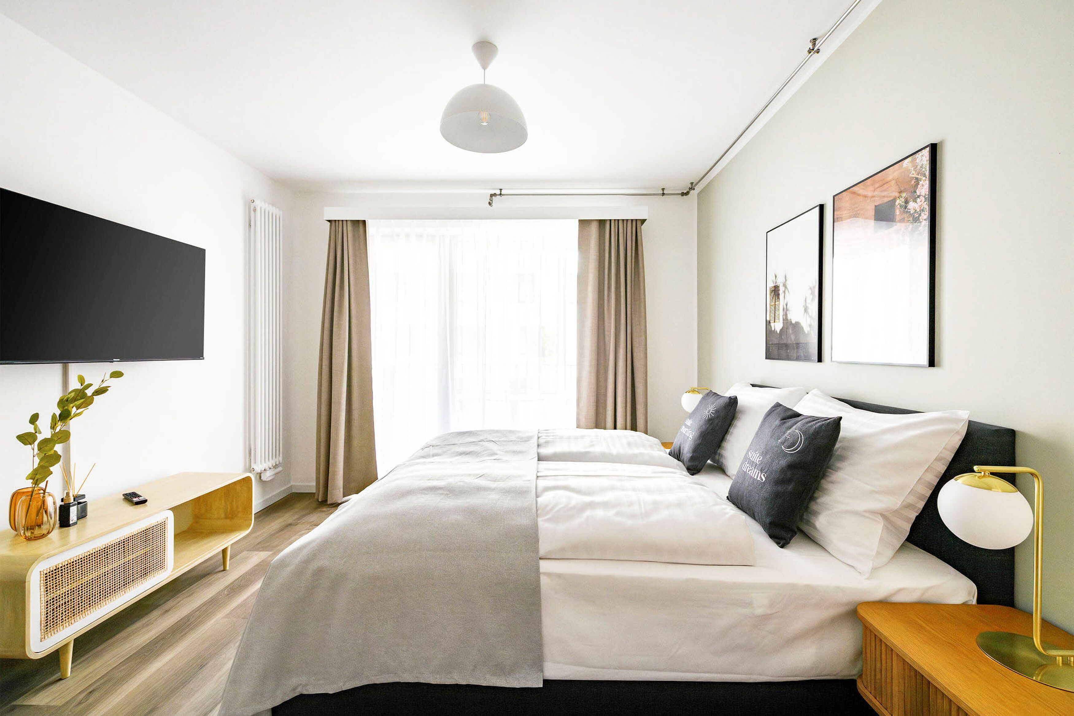 Ein modernes Hotelzimmer mit einem Bett, einem Flachbildfernseher, einem Nachttisch und einem an der Wand hängenden Kunstwerk.