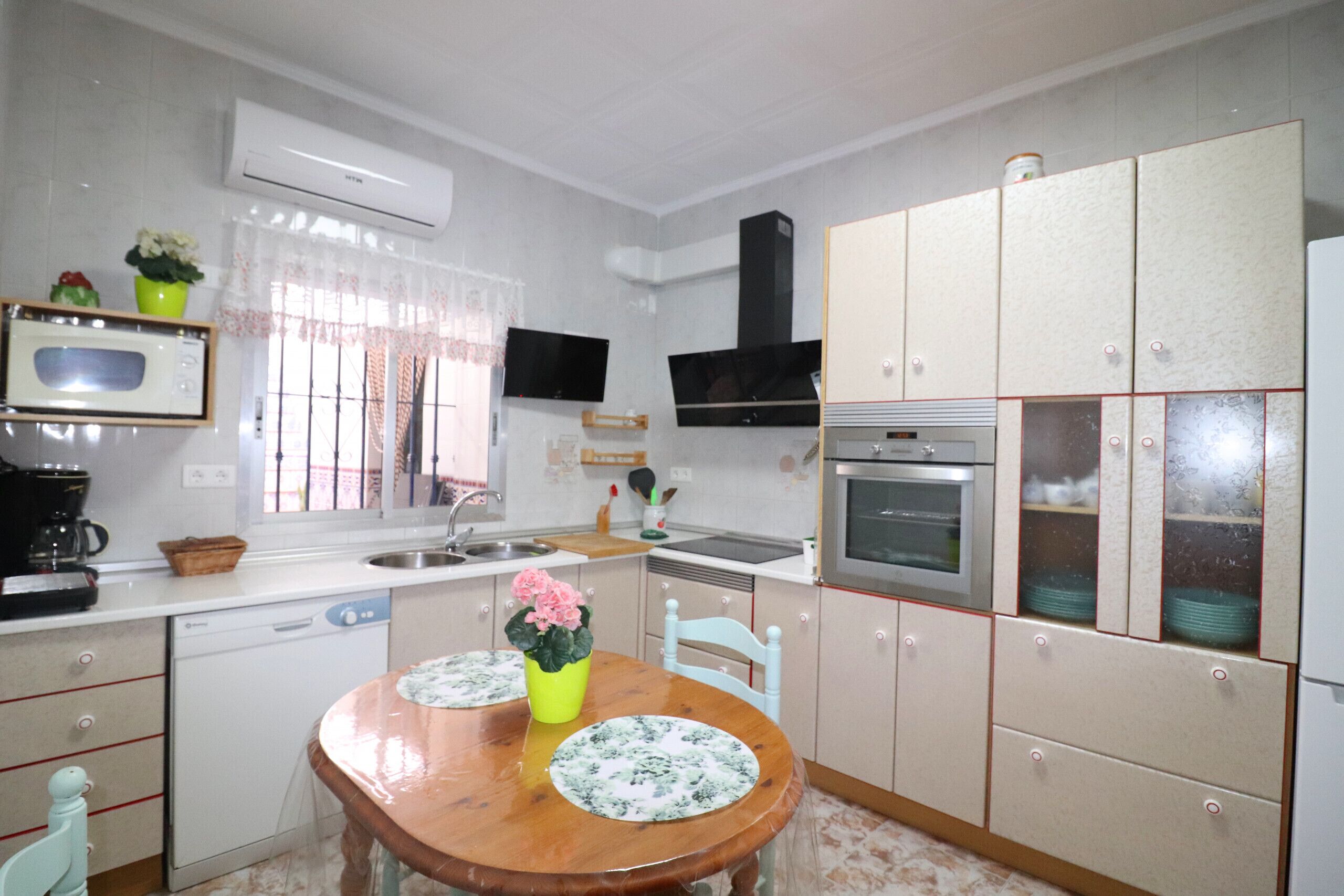 A kitchen with a wooden table, a dishwasher, a microwave, a stove, and cabinets.