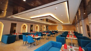 A modern dining area with blue seating, white tables, and recessed ceiling lighting. - Hotel Taj Crown Plaza (Agra)