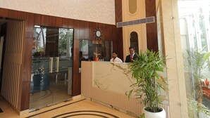 A hotel lobby with a large chandelier, a reception desk, and a potted plant. - Hotel Taj Crown Plaza (Agra)