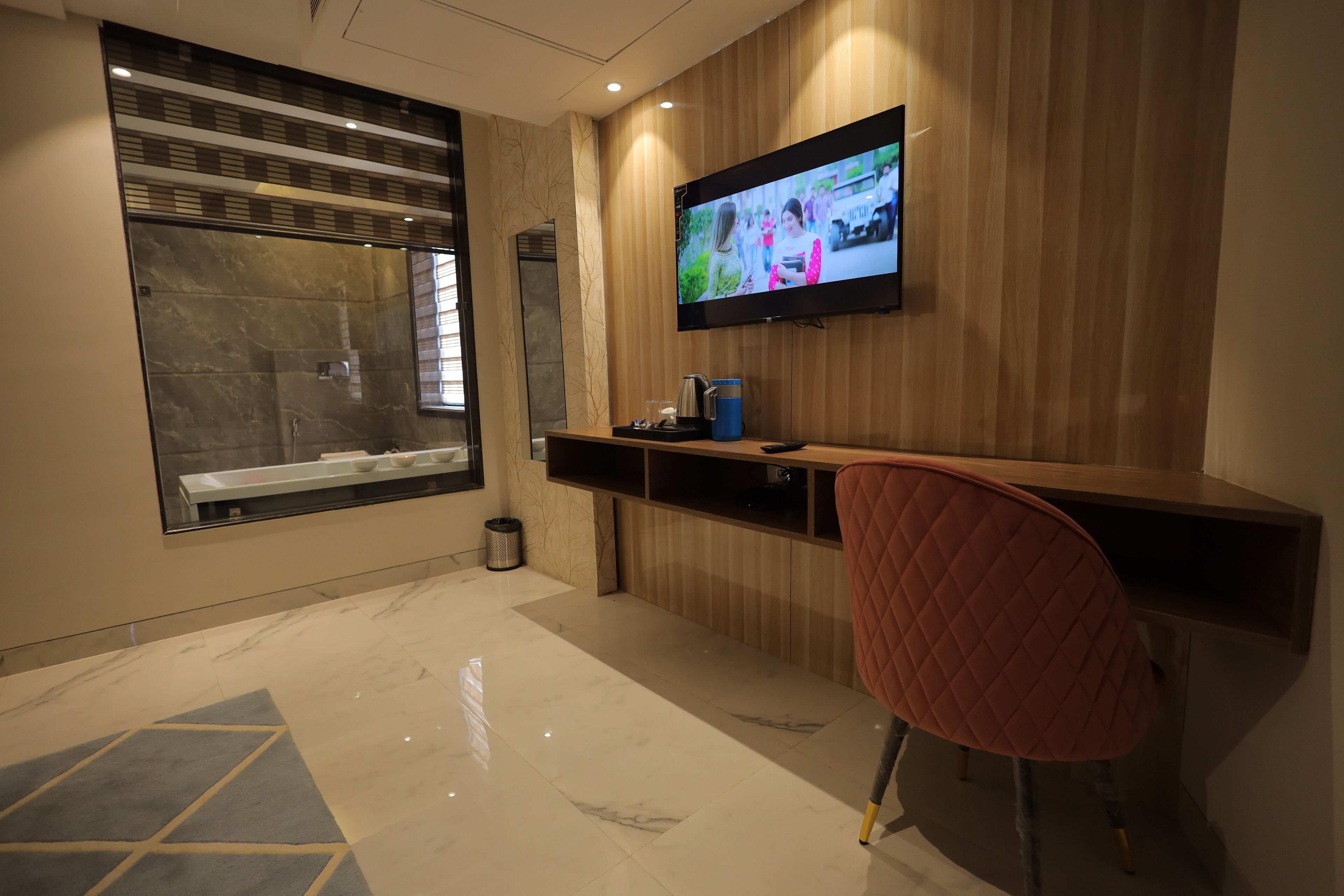 Un baño moderno con un espejo grande, una ducha, un lavamanos y un televisor montado en la pared.