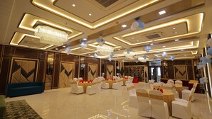 A spacious hall with a polished floor, tiered seating, and decorative lighting. - Hotel Taj Crown Plaza (Agra)