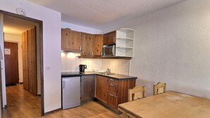 Une cuisine compacte avec des meubles en bois, un four à micro-ondes encastré et un petit lave-vaisselle.