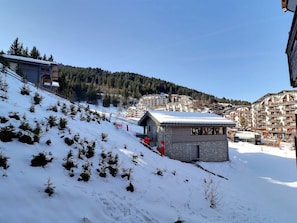 A snow-covered ski slope with a small lodge and a mountain town in the background.