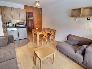 A compact living space with a kitchenette, a dining area, and a sofa.