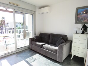 A living room with a grey sofa, a white dresser, and a painting on the wall.