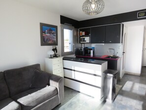 A compact living space with a kitchenette, a sofa, and a dining table.