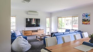 A modern living room with a sofa set, a coffee table, a TV, and a dining table.