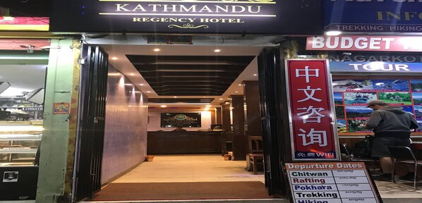 The entrance to Kathmandu Regency Hotel with a sign for "BUDGET NAGARKOT TOUR" and a list of departure dates for various activities. - MeroStay 229 Regency (Kathmandu)