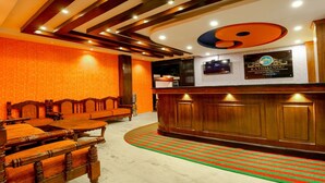Zona de recepción con un mostrador de madera, un sofá y una mesa de comedor.