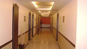 Un pasillo de hotel con piso de madera, paredes blancas y una pared roja al final.