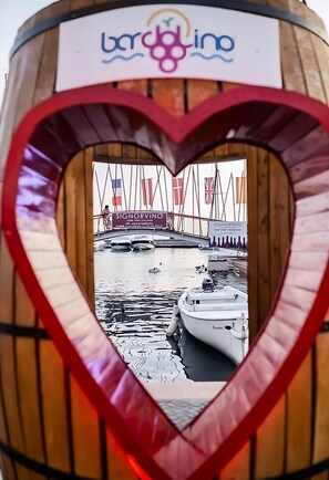 Un cadre en forme de cœur offrant une vue sur un port de plaisance, avec des bateaux et des drapeaux.