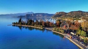 Blick auf das Wasser mit einem großen Riesenrad, ruhiger Wasserfläche und Bergen in der Ferne.