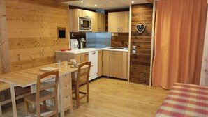 Quarto compacto com cozinha compacta, área de refeições e uma cama.