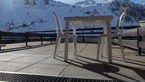 Mesa e cadeiras em um pátio ladrilhado, com vista para a montanha.