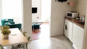 Une cuisine moderne équipée d’un four à micro-ondes, d’un lave-linge et d’un téléviseur fixé au mur.