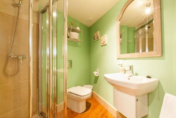 A bathroom with a glass shower enclosure, a white sink, and a toilet.