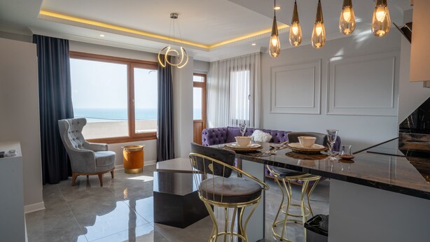 Een moderne keuken met een centraal eiland, hanglampen en uitzicht op zee.