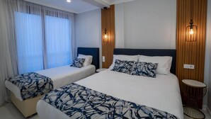 Een hotelkamer met twee bedden, een groot raam met gordijnen, een houten accentmuur en een ronde bijzettafel.