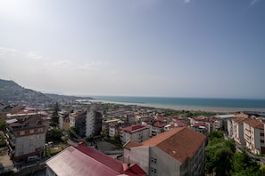 A coastal cityscape with buildings, a beach, and a bridge. - Shah Residence Hotel (Trabzon)