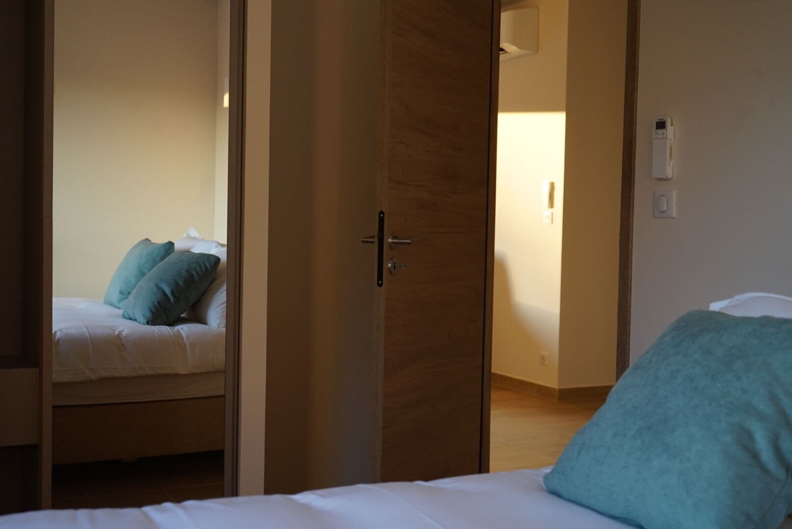 Ein Hotelzimmer mit einem Bett, einem Nachttisch und einer Tür zu einem anderen Raum.