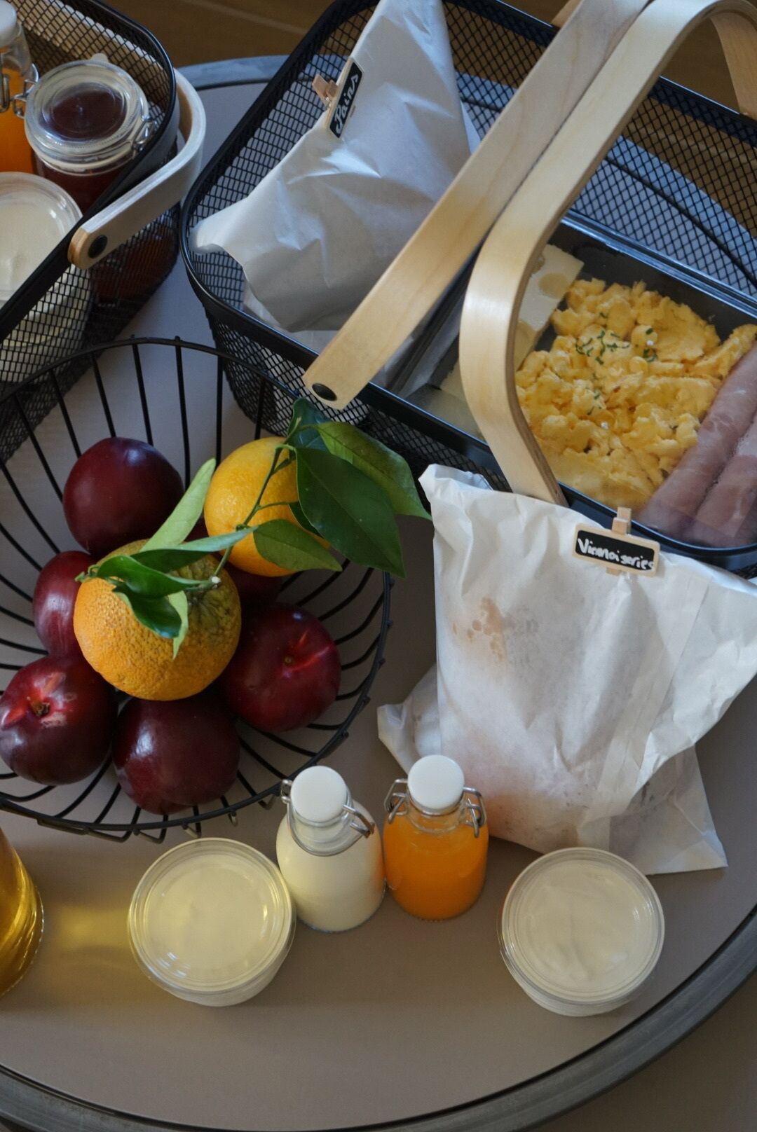 Bandeja con alimentos como manzanas, naranjas y un tazón de huevos revueltos, junto con condimentos y una servilleta.
