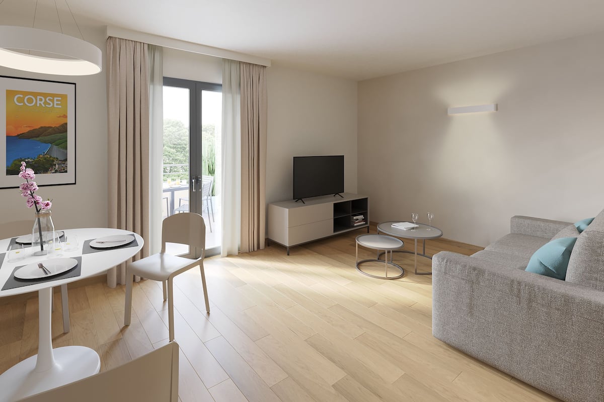 A modern living room with a grey sofa, a flat-screen TV on a white cabinet, a dining table with chairs, and a large window with curtains.