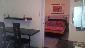 A small room with a bed, a desk, and a chair. There is a shelf above the desk and a picture on the wall. - Appartment Graz Zentrum (Graz)
