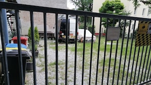 A gated area with a gravel path, a white van, and a red car parked in the background. - Appartment Graz Zentrum (Graz)