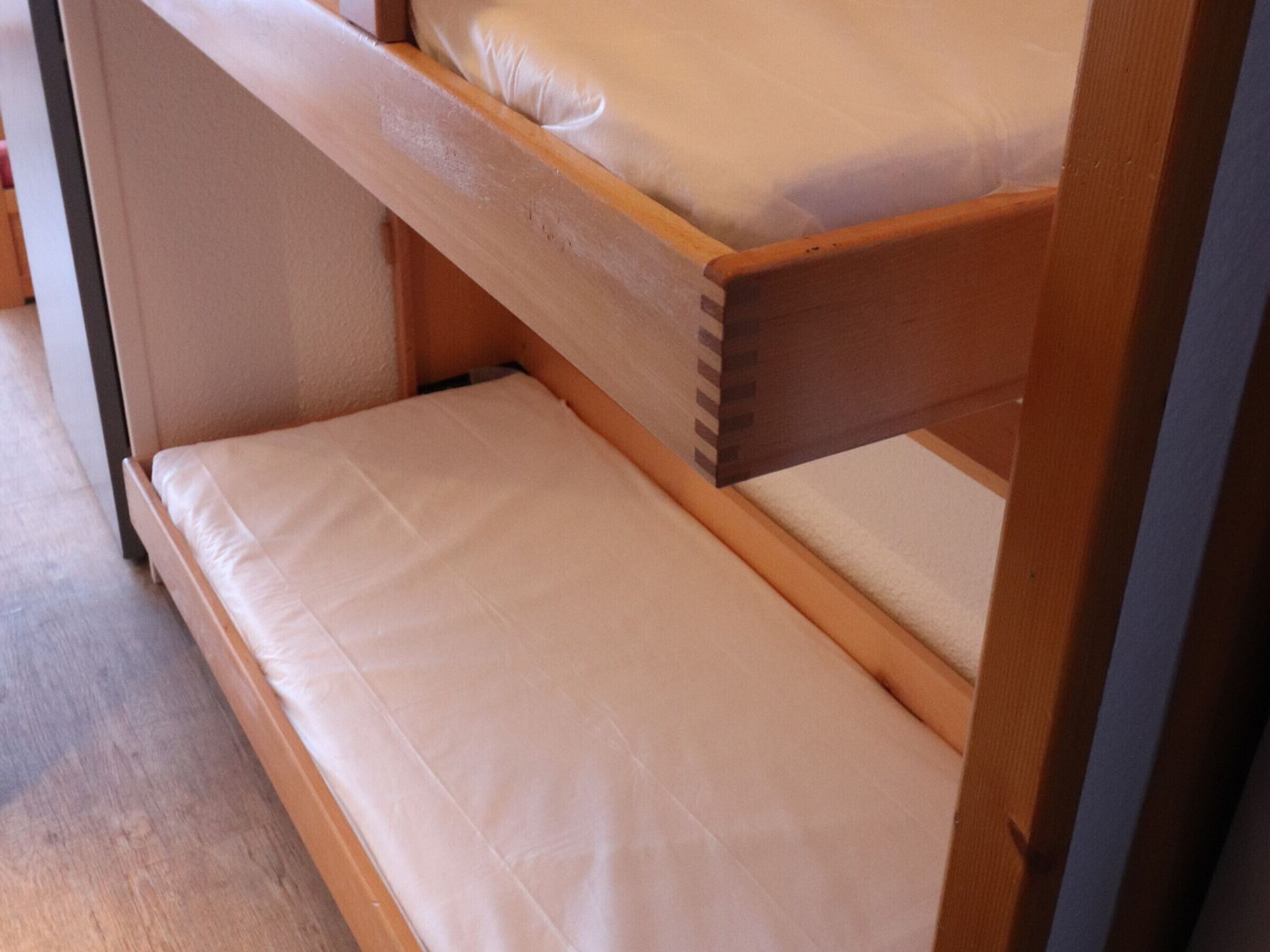 Een stapelbed met een houten frame en wit beddengoed.