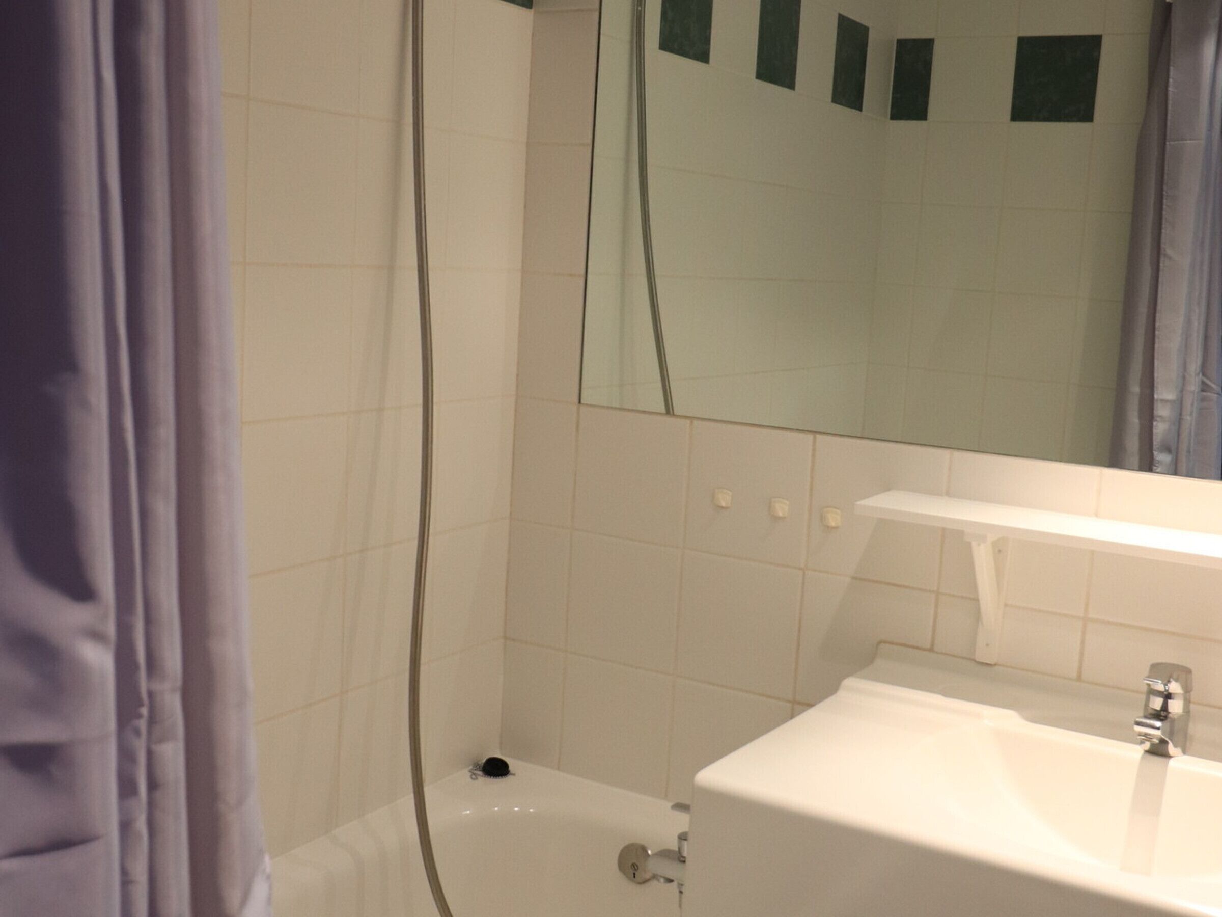 Une salle de bain avec une baignoire, un lavabo et un miroir.