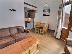 Ein gemütlicher Wohnbereich mit einer Couch, einem Holzespeisetisch, Stühlen, einer Küchenzeile und einem Bild an der Wand.
