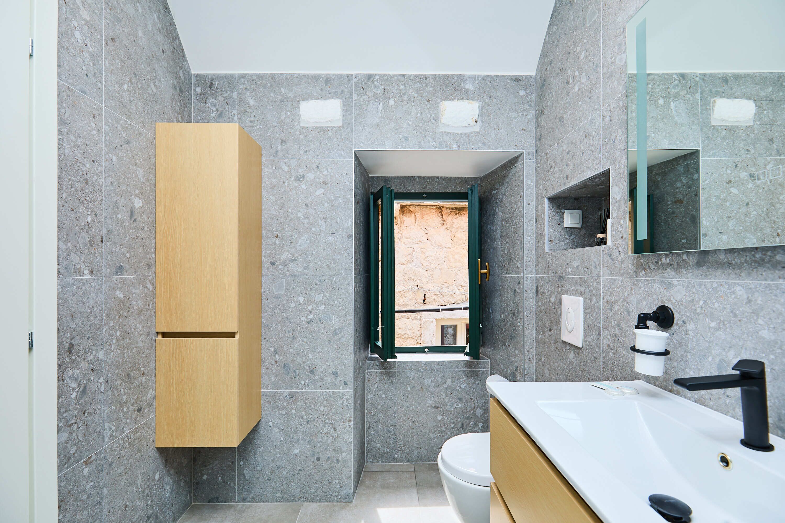A modern bathroom with a wooden cabinet, a white sink, and a mirror.