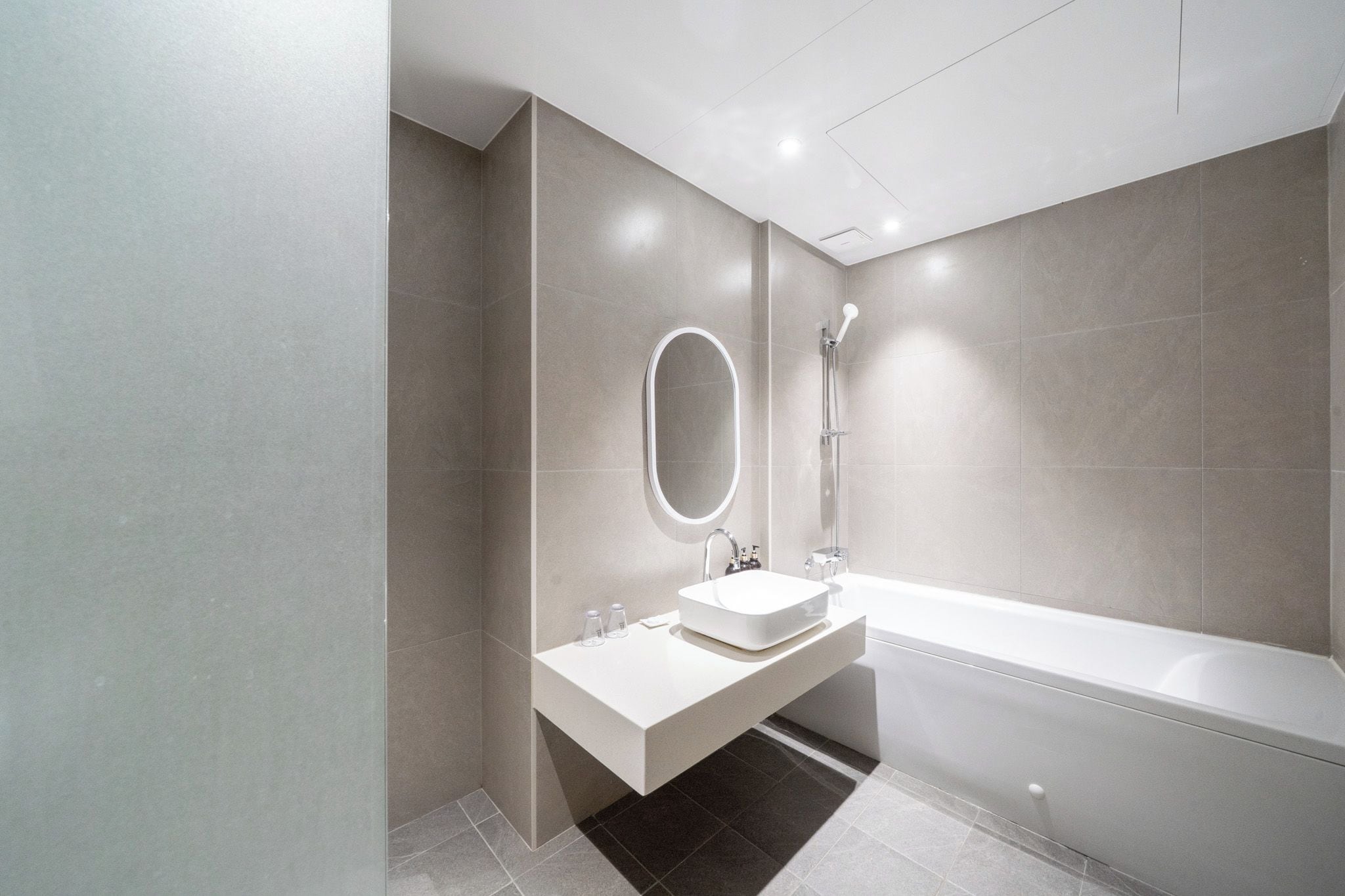 A modern bathroom with a rectangular sink, a mirror, and a freestanding bathtub.